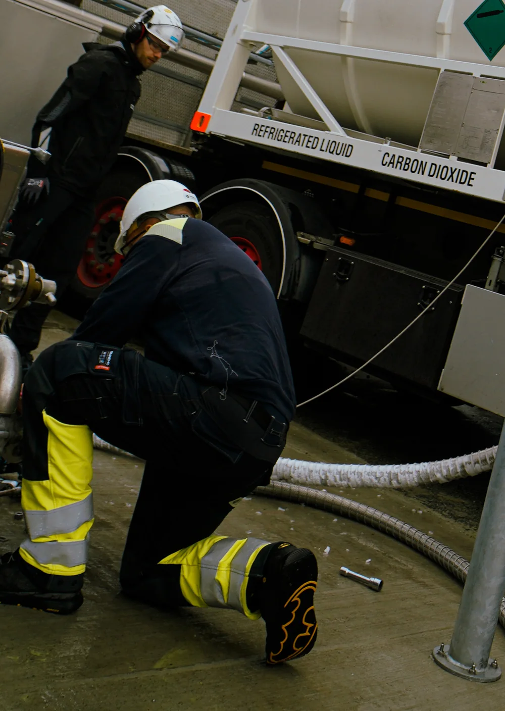 Technician in a white hard hat connecting the transfer hose of a Bofort cryogenic ISO tank