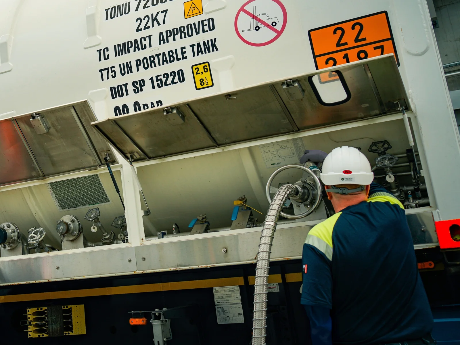 Technician in a white hard hat and protective clothing at the valve cabinet of a Bofort liquid CO2 ISO tank